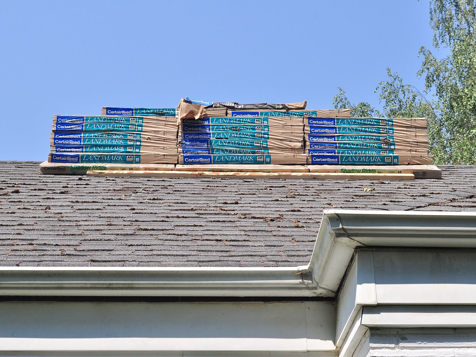Bundles of new architectural shingles staged on a roof ridge before installation